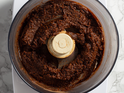 Figues, dattes et épices partiellement mélangées dans le bol d’un robot culinaire